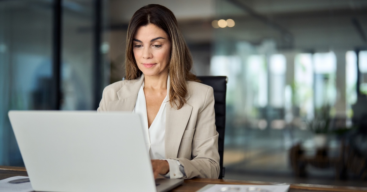 A professional working on a laptop at a desk in a modern office environment.