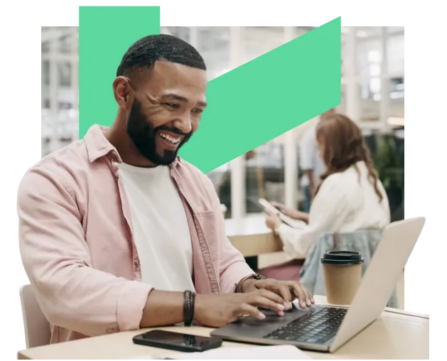 Smiling man in an office with a laptop and a coffee cup
